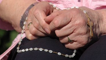 Rosenkranz in den Händen eine älteren Frau
