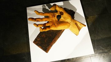 Überdimensionale Hand auf einen Eichenbalken genagelt