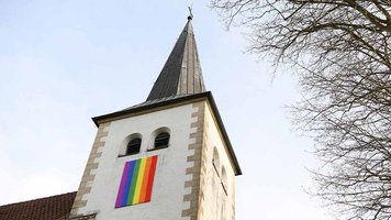 Die Regenbogenfahne, Zeichen der LGBTIQ+-Community, am Kirchturm der St.-Petronilla-Kirche in Handorf. Die Aktion "OutInChurch" setzt sich für eine "Kirche ohne Angst" ein. 