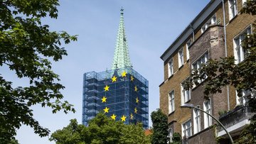 Ein Kirchturm ist mit einer EU-Flagge eingerüstet.
