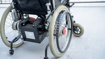 Ein Rollstuhl steht im linken Teil des Bildes.