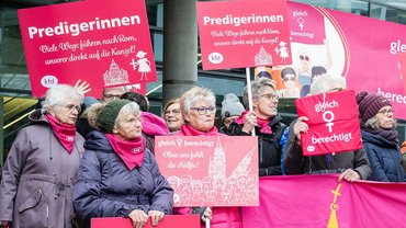 Demonstrierende Frauen. Plakate fordern Reformen in der Kirche