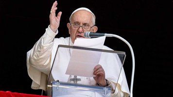 Papst Franziskus mit Manuskript am Rednerpult am Fenster