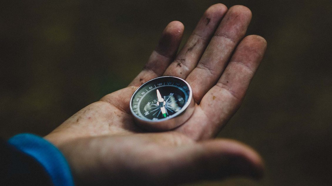 Ein Kompass liegt in einer schmutzigen Hand. Foto: pixabay.com