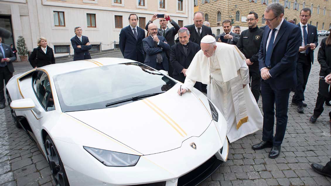 Papst Franziskus unterschreibt auf dem Lamborghini.