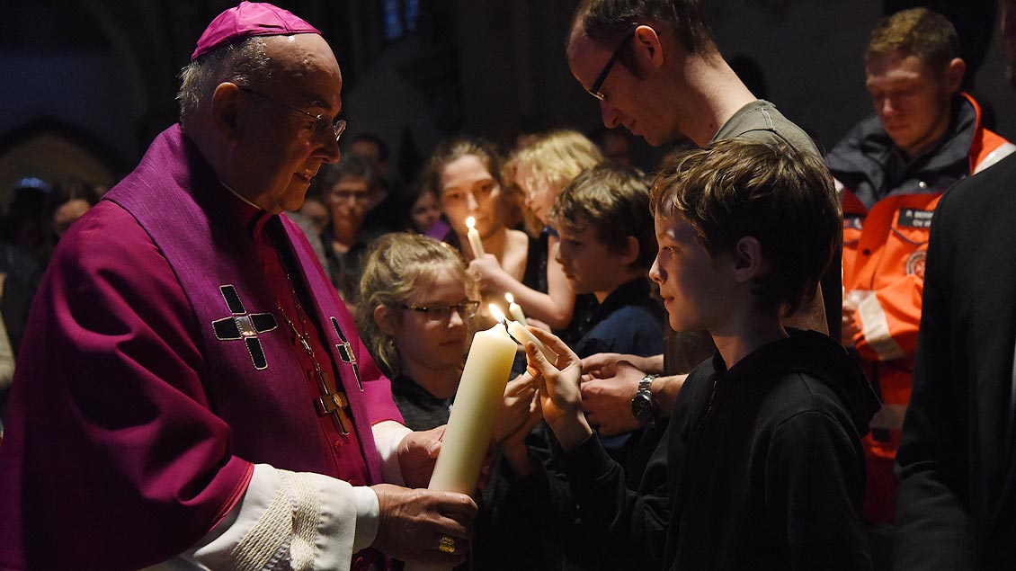 Bischof Felix Genn zündet im Gedenkgottesdienst die Kerzen der Menschen im Dom an.