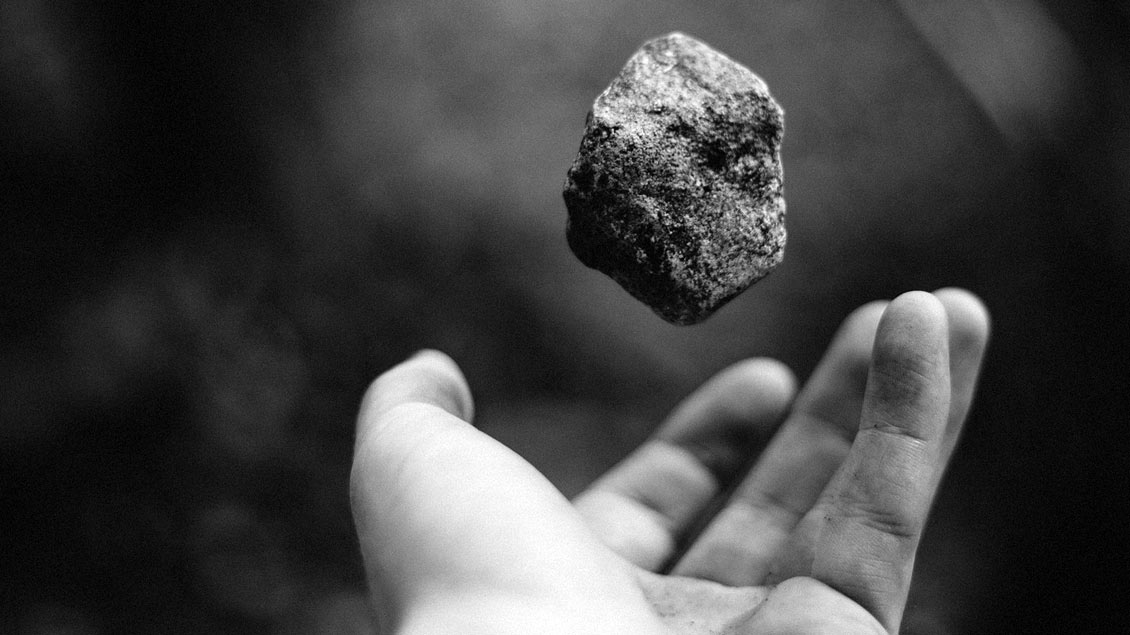 Eine Hand wiegt und wirft einen Stein