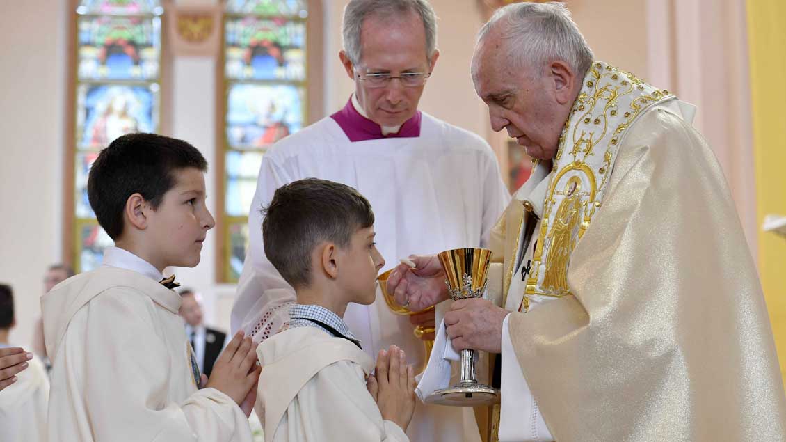 Der Papst teilt die Erstkommunion an Kinder aus