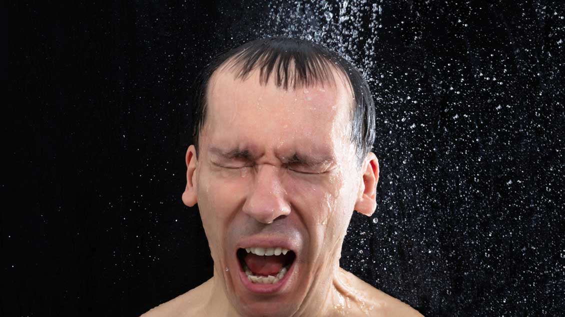 Ein Mann steht unter einer kalten Dusche. Foto: Andrey Popov (Shutterstock)