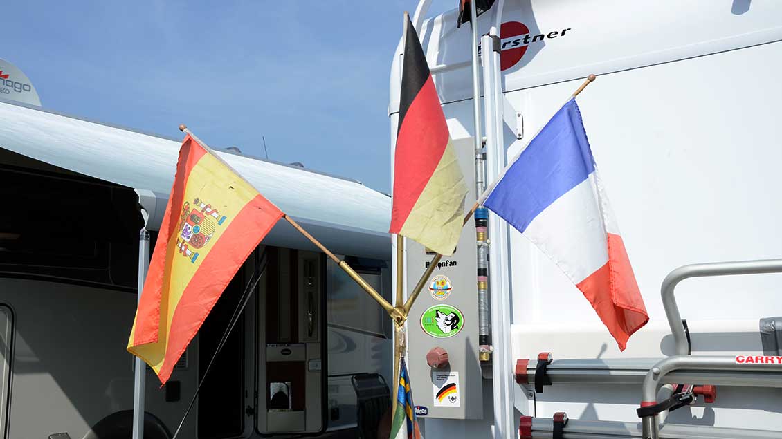 Spanische, Deutsche und Französische Flagge an der Rückseite eines Reisemobils.