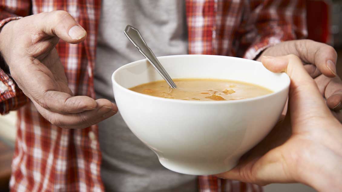Ein Mensch bekommt einen Teller Supper Foto: SpeedKingz (Shutterstock)