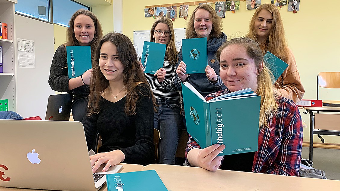 Sechs Schülerinnen des Alexandrine-Hegemann-Berufskollegs sitzen auf einer Schulbank und haben das Buch aufgeschlagen. 
