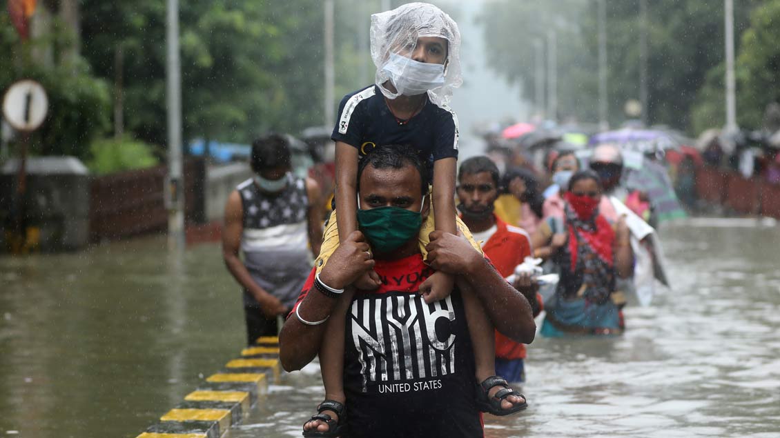 Mann trägt Junge in Mumbai druch überschwemmte Straßen. Foto: Francis Mascarenhas (Reuters)