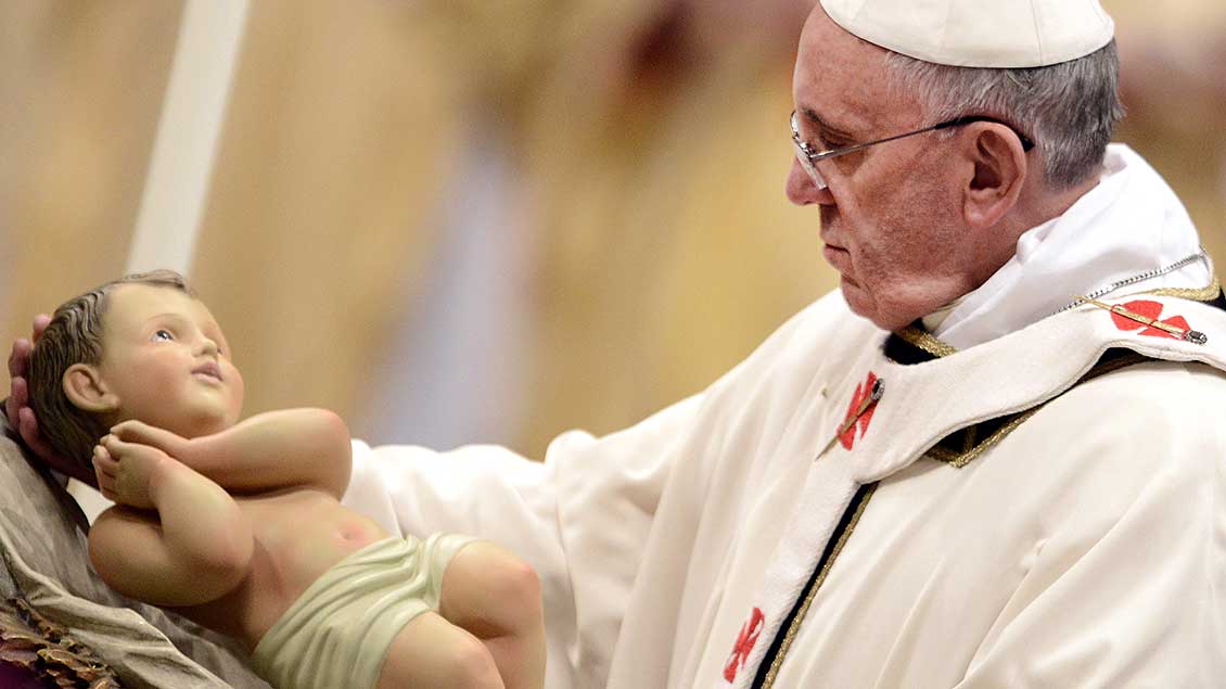Papst Franziskus hält das Jesuskind in der Christmette 2013