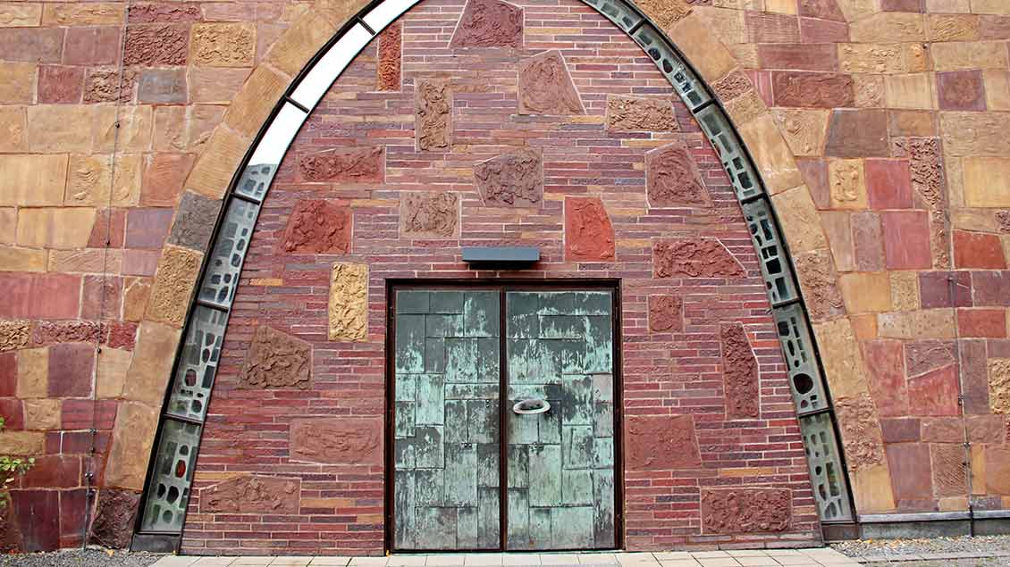 Markant sind die Kirchentür und die teils aus Hochofenschlacke geformten Fassadensteine. | Foto: Johannes Bernard
