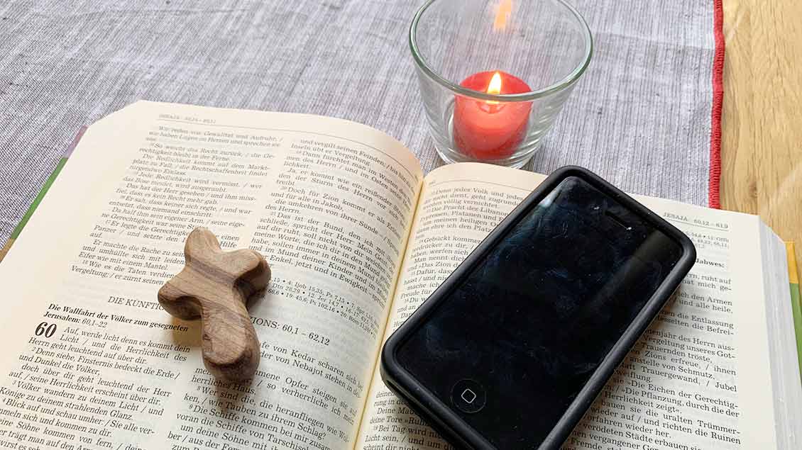 Eine Bibel, ein Handy und eine Kerze Foto: Marie-Theres Himstedt