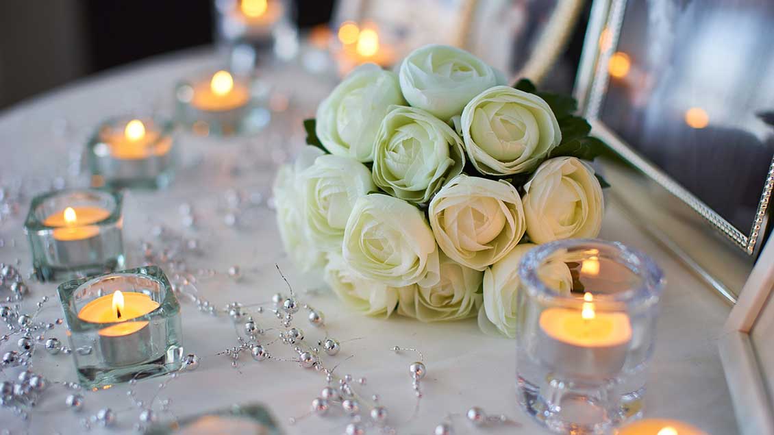 Kerzen und Blumen auf einem Hochzeitstisch