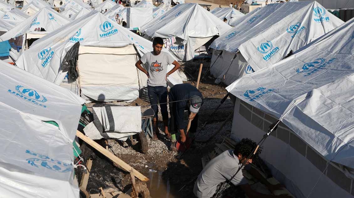 Männer reparieren ein Zelt nach einem Sturm im Oktober in einem Lager auf Lesbos, Griechenland. 