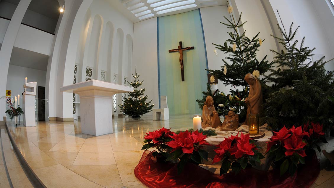 Eine weihnachtlich geschmückte Kirche mit Krippe.