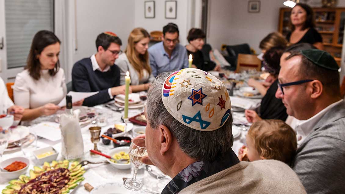 Eine Familie am großen Esstisch feiert das jüdische Neujahrsfest „Rosch Haschana“.