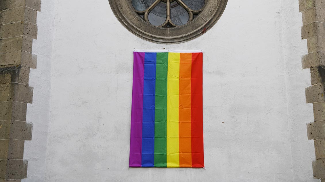 Eine Regenbogenfahne hängt an der Kirche.