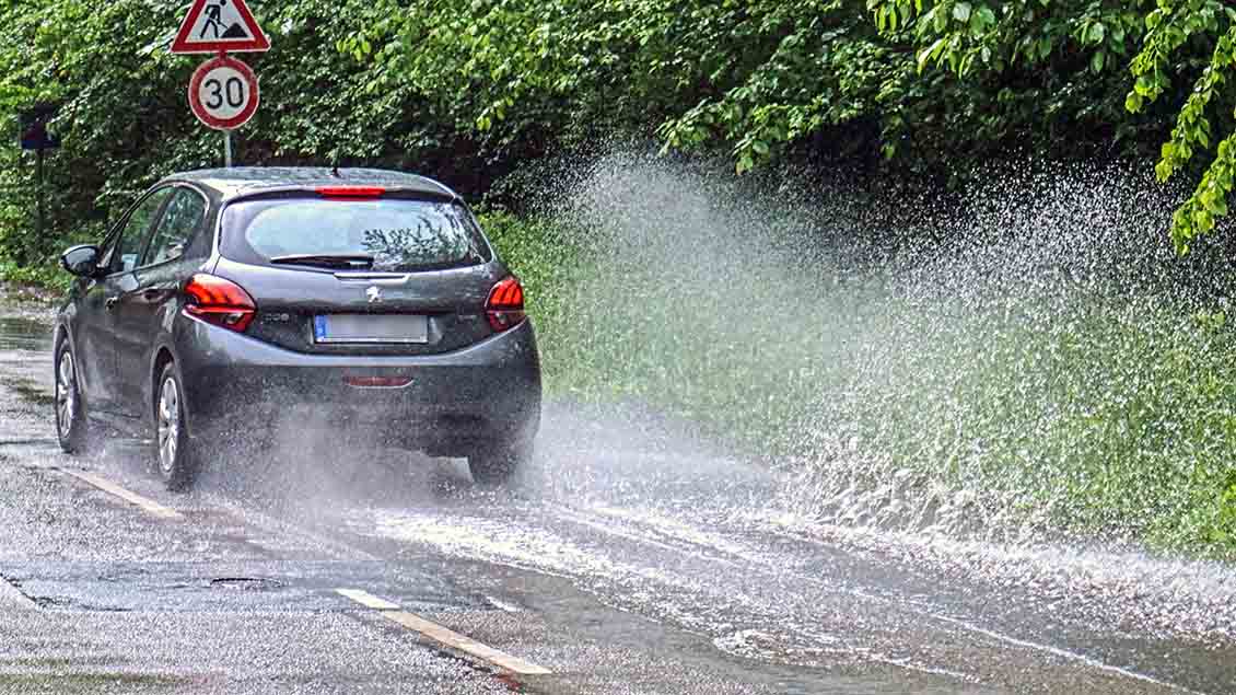 Ein Auto fährt durch eine tiefe Wasserpfütze. Foto: Gottfried Czepluch (imago)