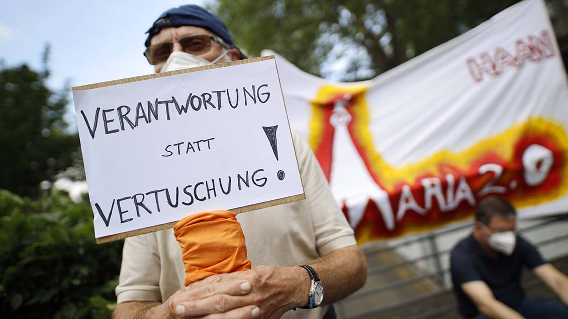 Ein Demonstrant hält in Köln ein Plakat hoch.