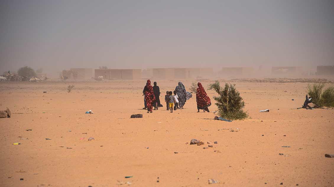Menschen sind auf einer Straße aus Sand unterwegs Foto: Le Pictorium (imago)