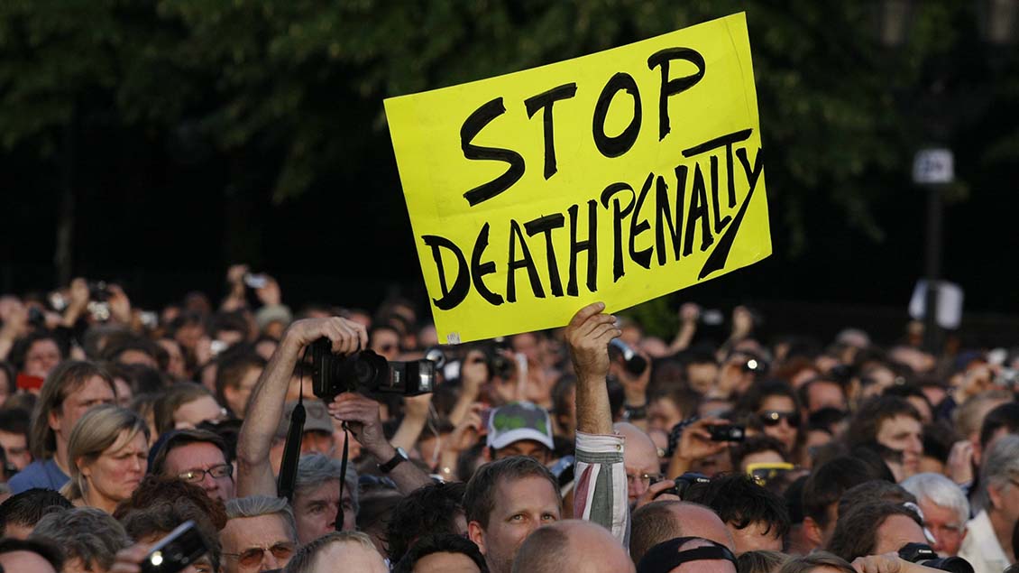 Auf einer Demo wird ein Schild mit "Stop Death Penalty" hoch gehalten.