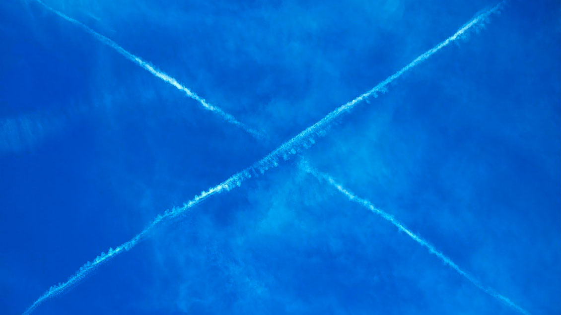 Bild des Himmels mit zwei gekreuzten Kondensstreifen.