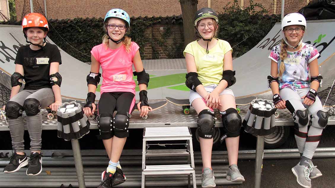 Matilda, 12 Jahre, Marit, 11 Jahre, Abigail, 12 Jahre und Lara, 11 Jahre, freuen sich über die Gelegenheit, Skateboard in der Schule zu fahren.