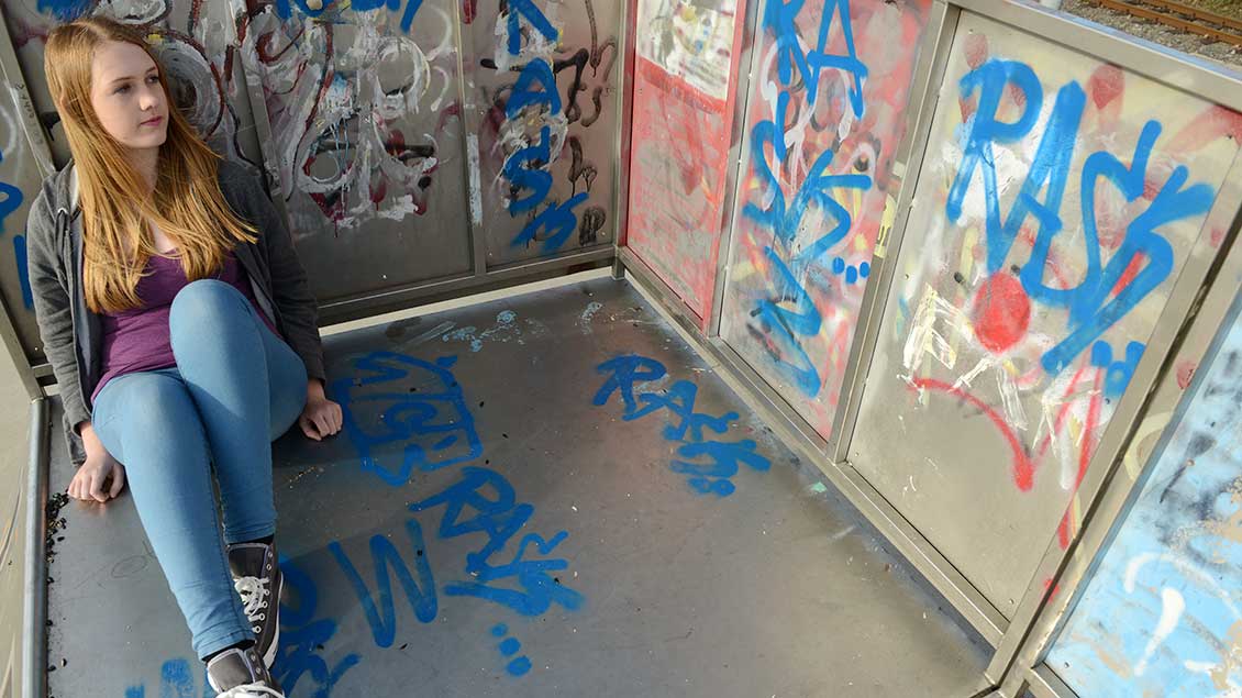 Junge Frau in Gedanken vor einem Grafiti. Foto: Michael Bönte