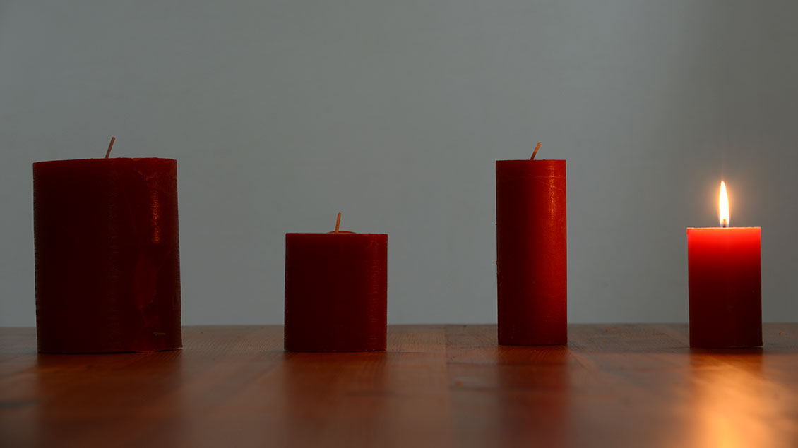 Vier Adventskerzen mit einer brennenden Kerze Foto: Michael Bönte