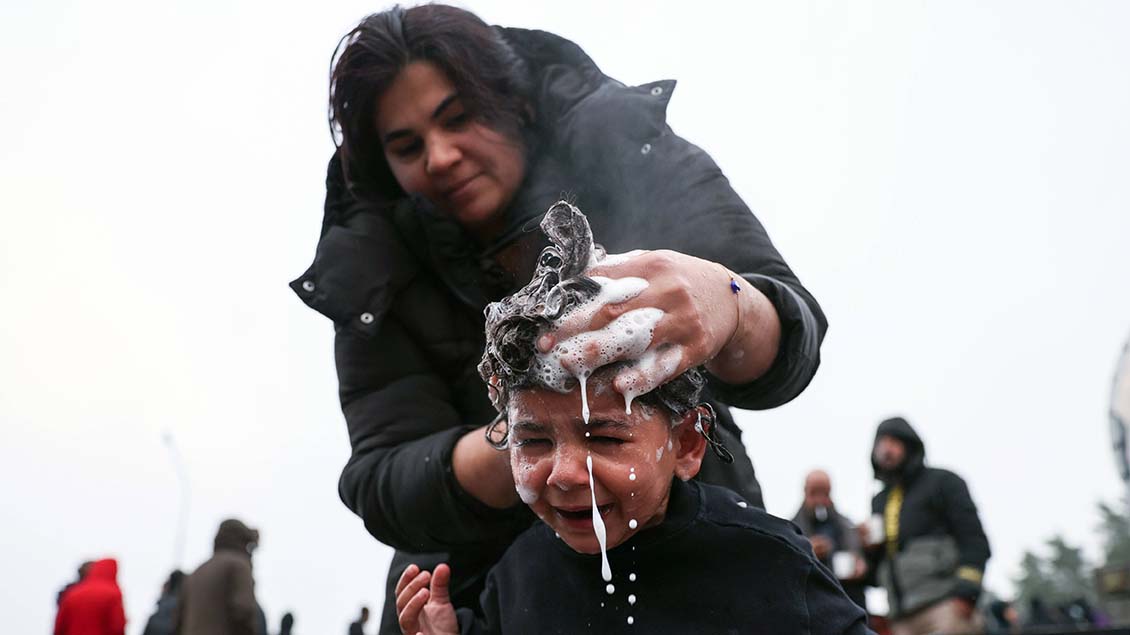 Eine Frau wäscht einem Kind die Haare im Flüchtlingslager