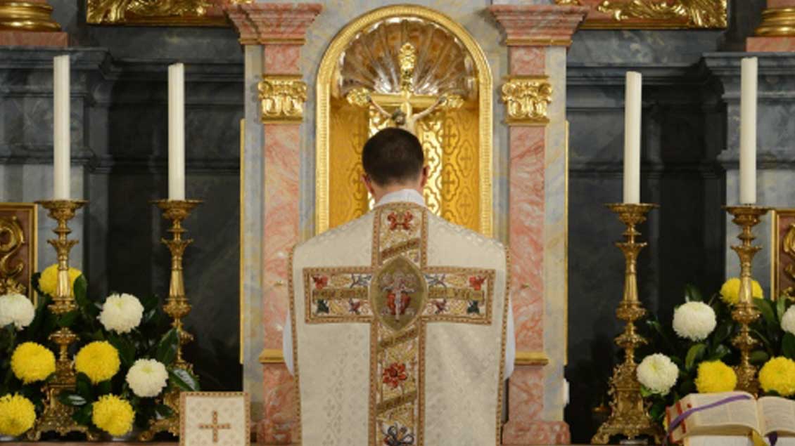 Priester in Rückenansicht vor dem Altar. 