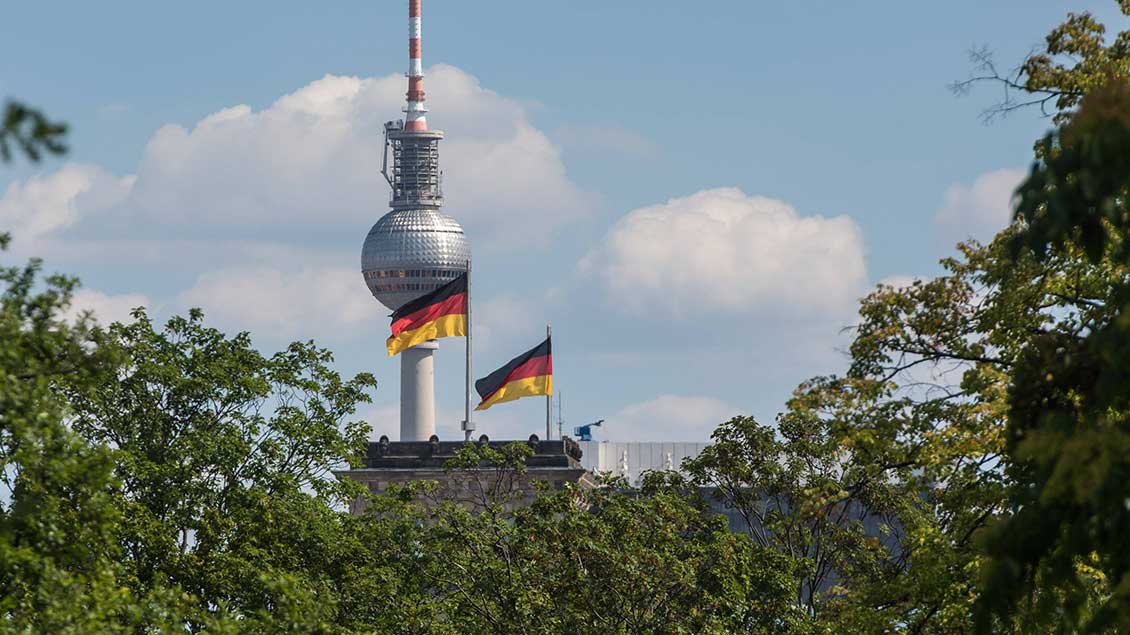 Deutschlandfahnen vor Berliner Fernsehturm mit Kreuz Foto: Christian Ditsch (Imago)