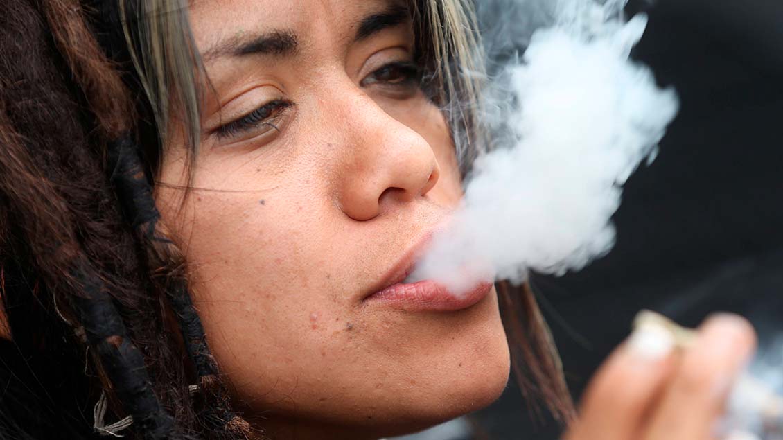 Frau raucht Zigarette mit Marihuana