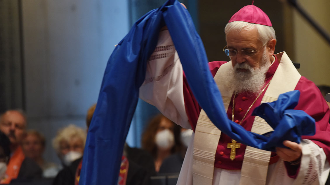 Bischof Feige legt im Ökumenischen Gottesdienst ein blaues Tuch vor den Altar. | Foto: Michael Bönte