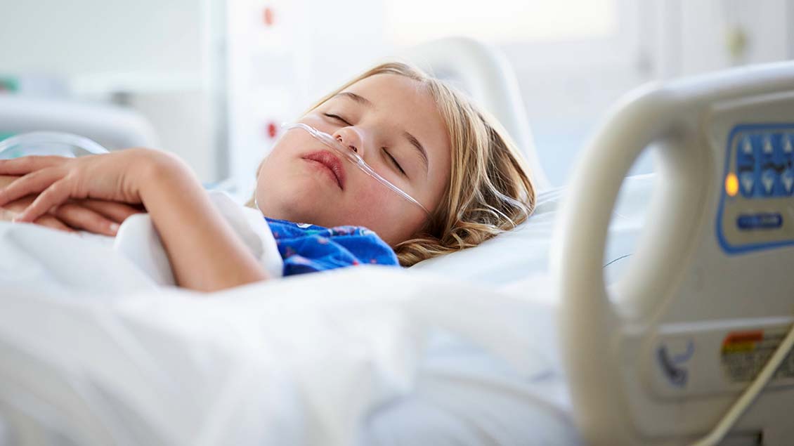Kind liegt schlafend in einem Krankenhausbett