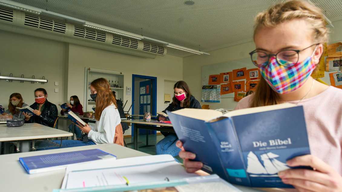 Eine Schülerin liest in einer Bibel. Foto: imago