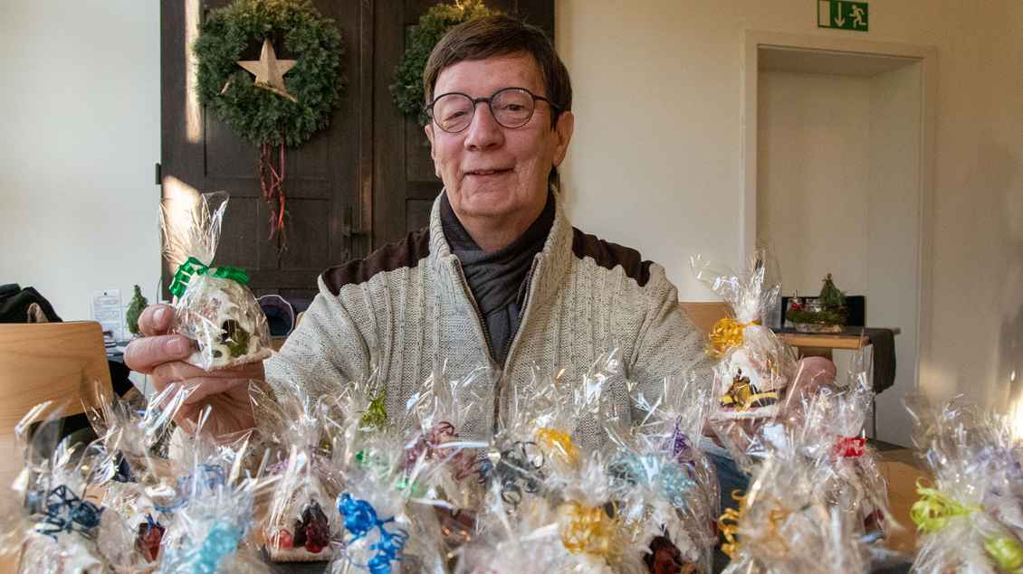 Wolfgang Pietrusiak hält Tüten mit Weihnachtshäuschen in der Hand.