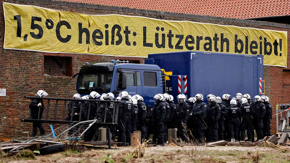 Polizisten vor einem Banner mit der Aufschrift "Lützerath bleibt" Foto: Christoph Hardt (Panama Pictures / Imago)