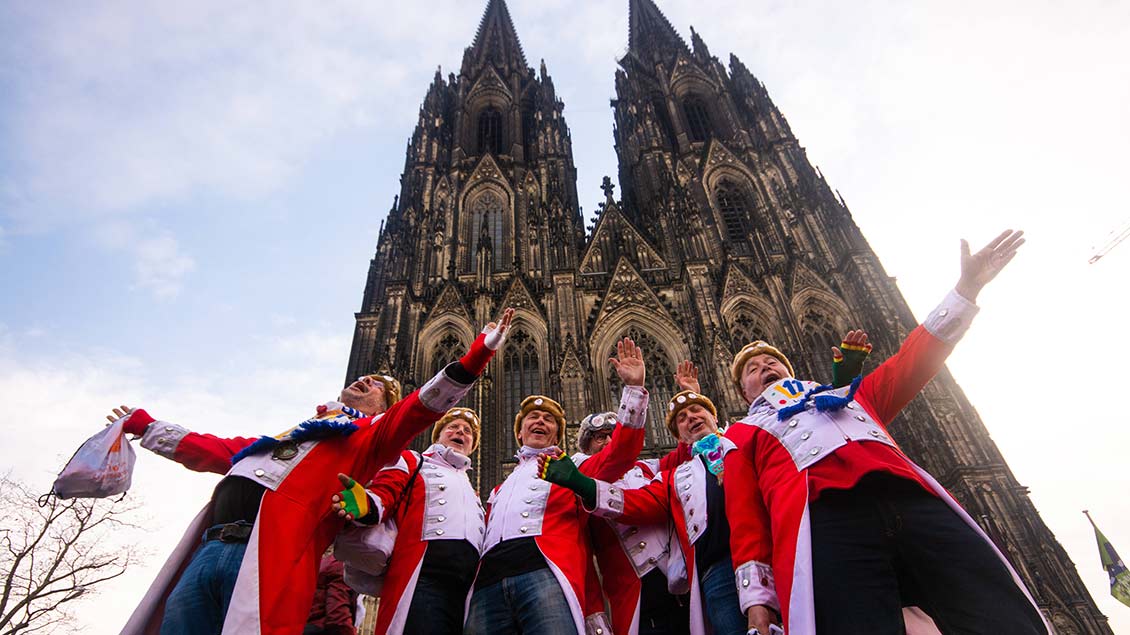 Karnevalisten feiern und singen vor dem Kölner Dom.
