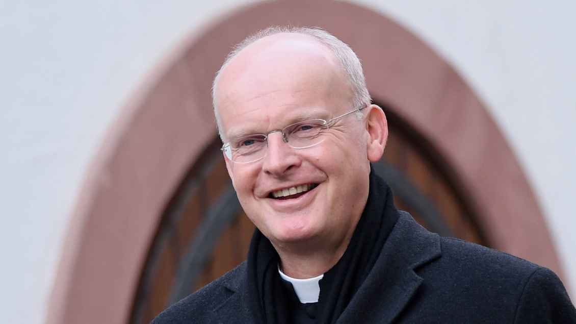 Bischof Overbeck in einem schwarzen Mantel. Er lächelt. Foto: ULMER Pressebildagentur (imago)