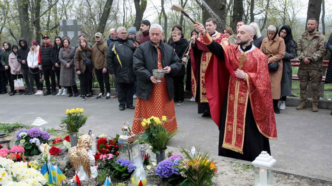 Ein Priester segnet Gräber bei einer Trauerfeier in Kiew in der Ukraine