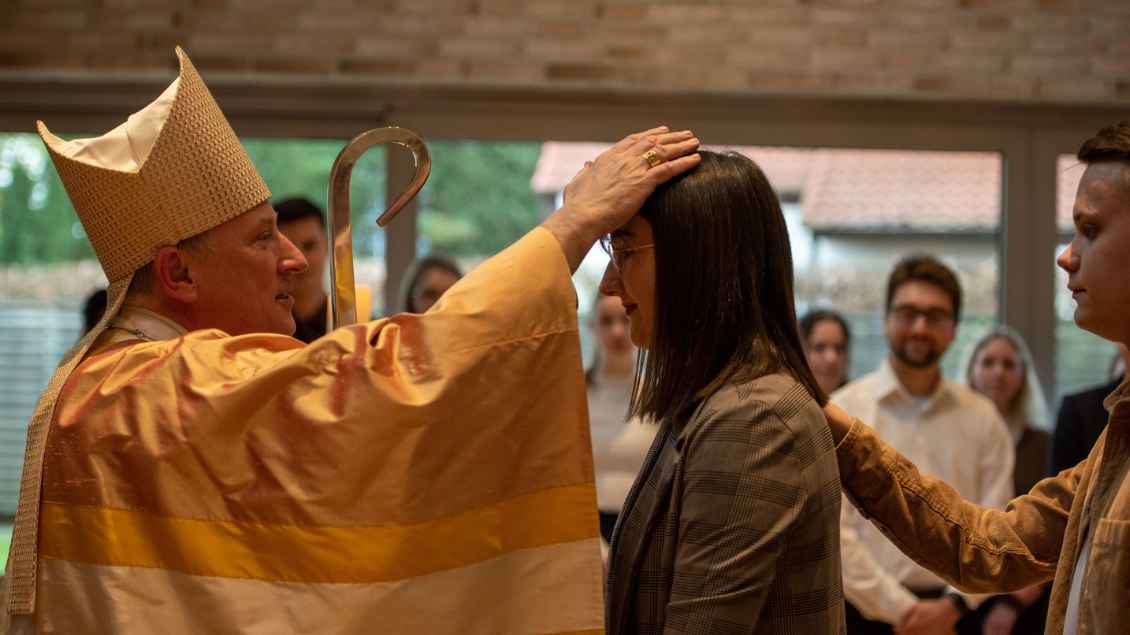 Weihbischof Theising legt die Hand auf den Kopf einer Frau. Foto: bpv