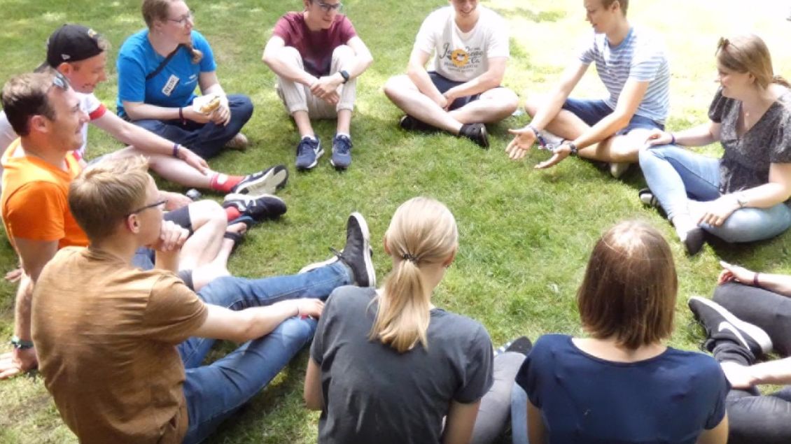 Junge Menschen sitzen in einem Kreis.