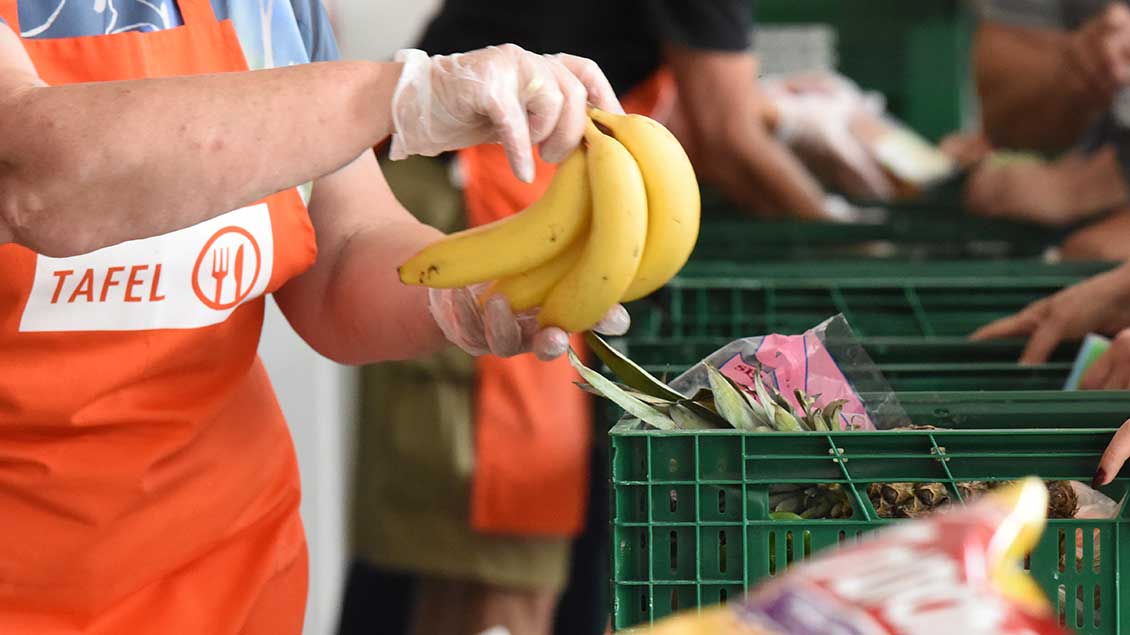 Ein Mitarbeiter der Tafel hält Bananen in der Hand. Foto: Michael Bönte