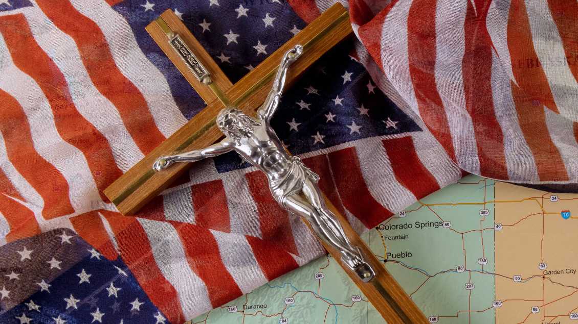 Ein Kreuz liegt auf einer US-Flagge Foto: Shotshop (Imago)