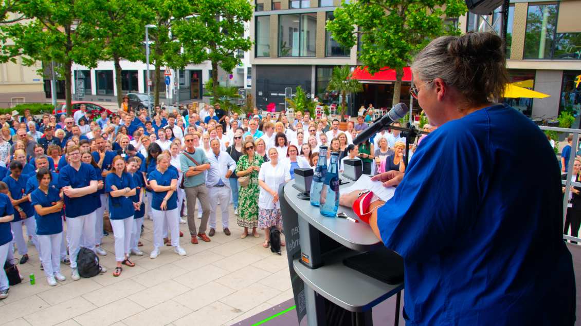 Die Cloppenburger Krankenpflegerin Ruth Fangmann spricht zu vielen Pflegekräften in blauen Hemden